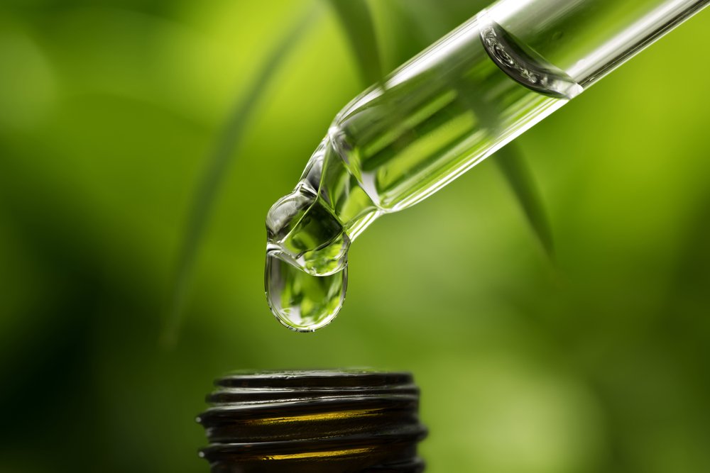 Photo of a herbal tincture bottle with fresh herbs and flowers in the background.
